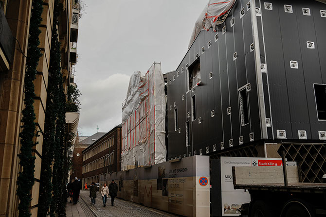 Blich auf ein Gebäude das im Bau ist.  Eine dunkelgrau Fassade ist zu sehen.