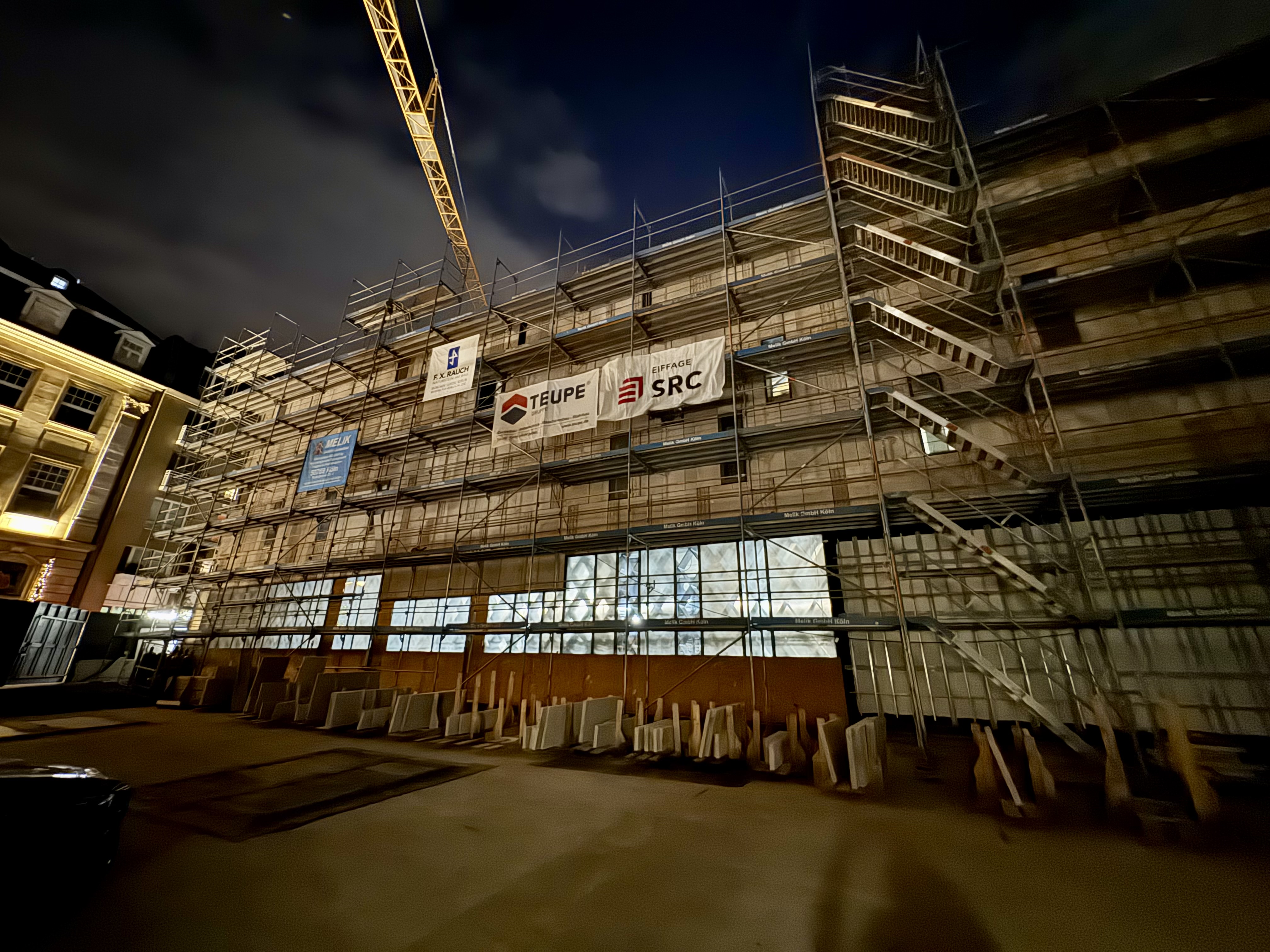 Ein zweistöckiges Gebäude mit einer weißen Steinfassade ist von einem Baugerüst ummantelt.