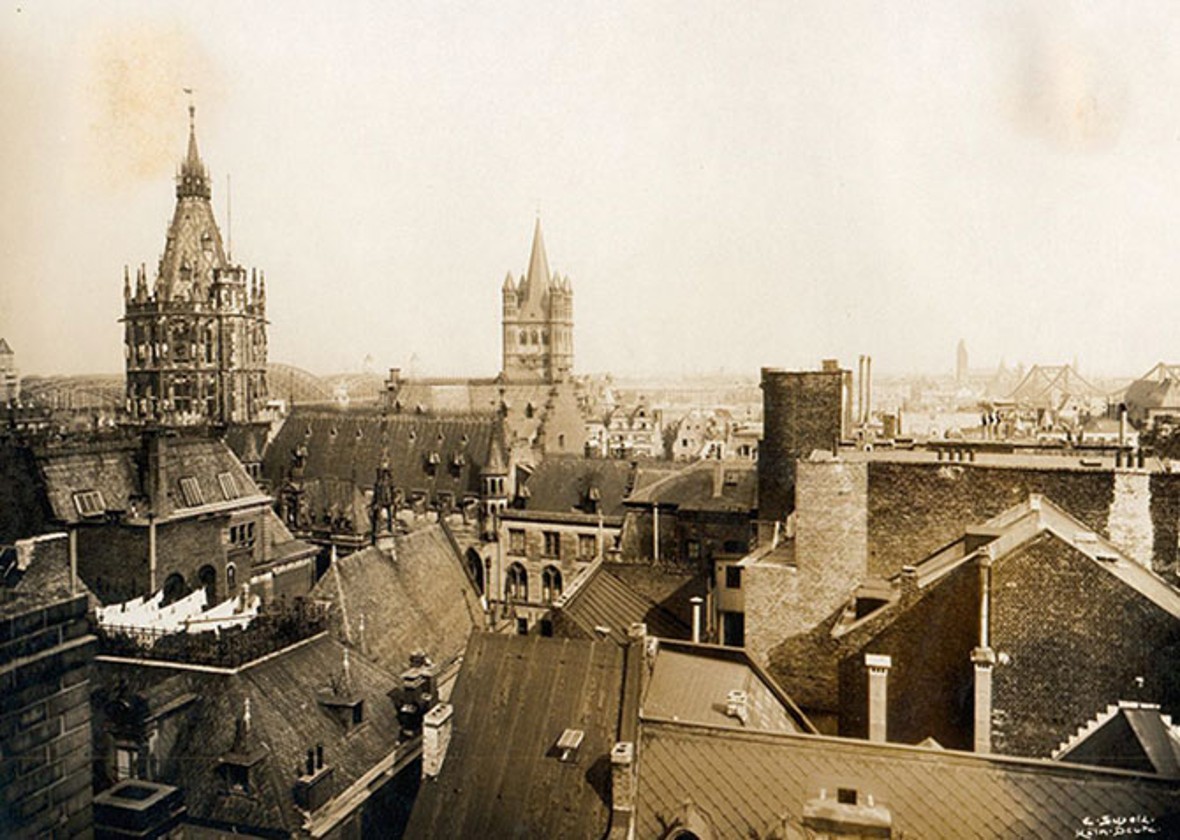 Das Schwarz-Weiß-Bild zeigt einen Blick vom Farina-Haus in Köln auf das Kölner Rathaus. Die Aufnahme von 1927 gibt einen Eindruck davon, wie dicht das jüdische Viertel bebaut war. Im Zentrum die nach 1424 in die Ratskapelle umgewandelte, ehemalige Synagoge.