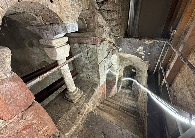 Eine Treppe führt hinunter in den Schacht der Mikwe. Rundbögen sind oben an der Treppe zu sehen.