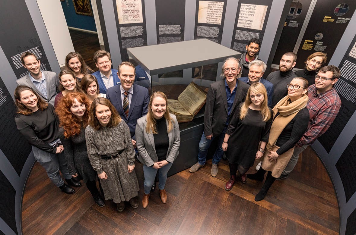 Das MiQua-Team bei der Eröffnung der Ausstellung zum Amsterdam Machsor. Im Hintergrund ist die Vitrine mit dem Amsterdam Machsor zu sehen.