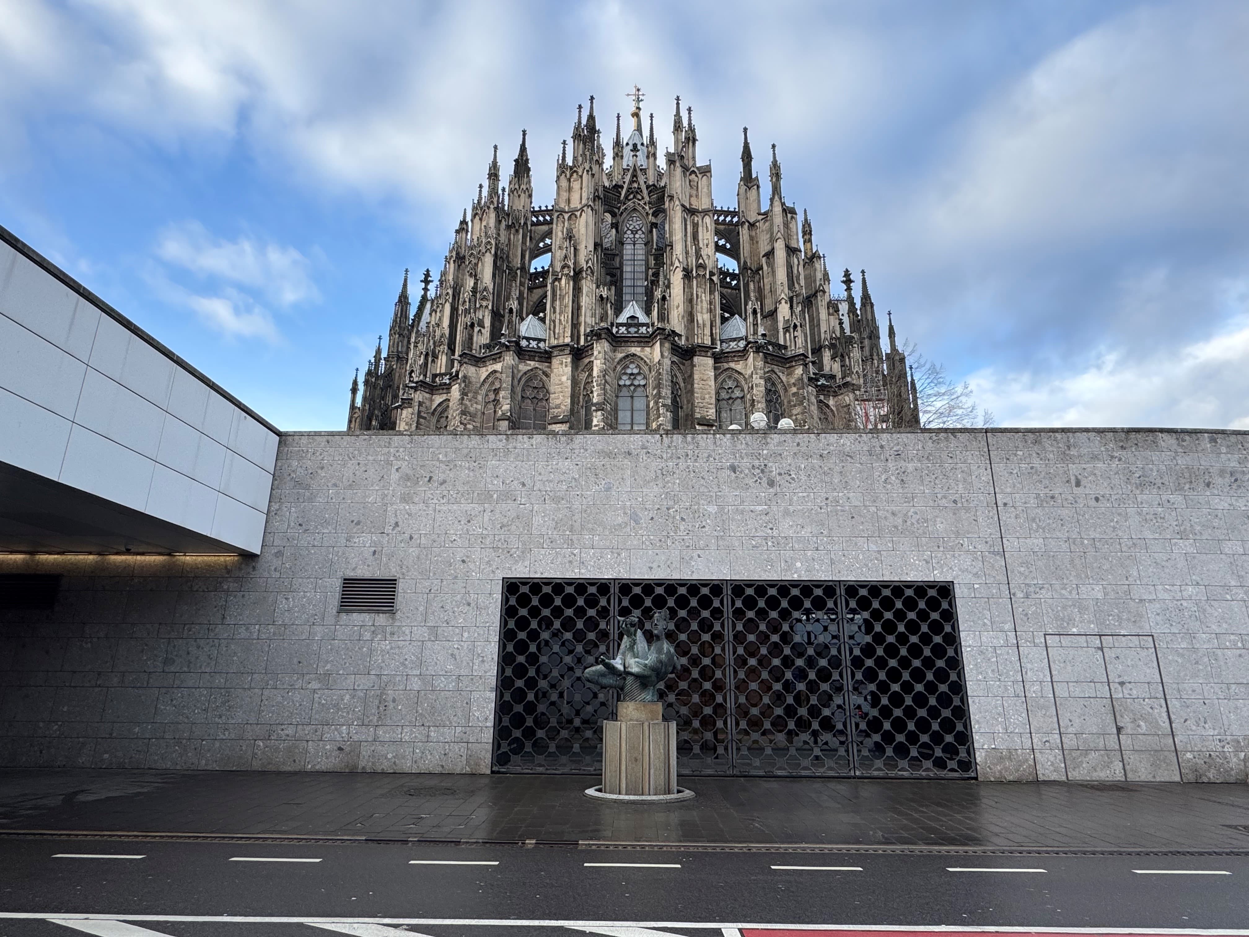 Ein Eingang in ein Gebäude. Dahinter ist eine große Kirche zu sehen.
