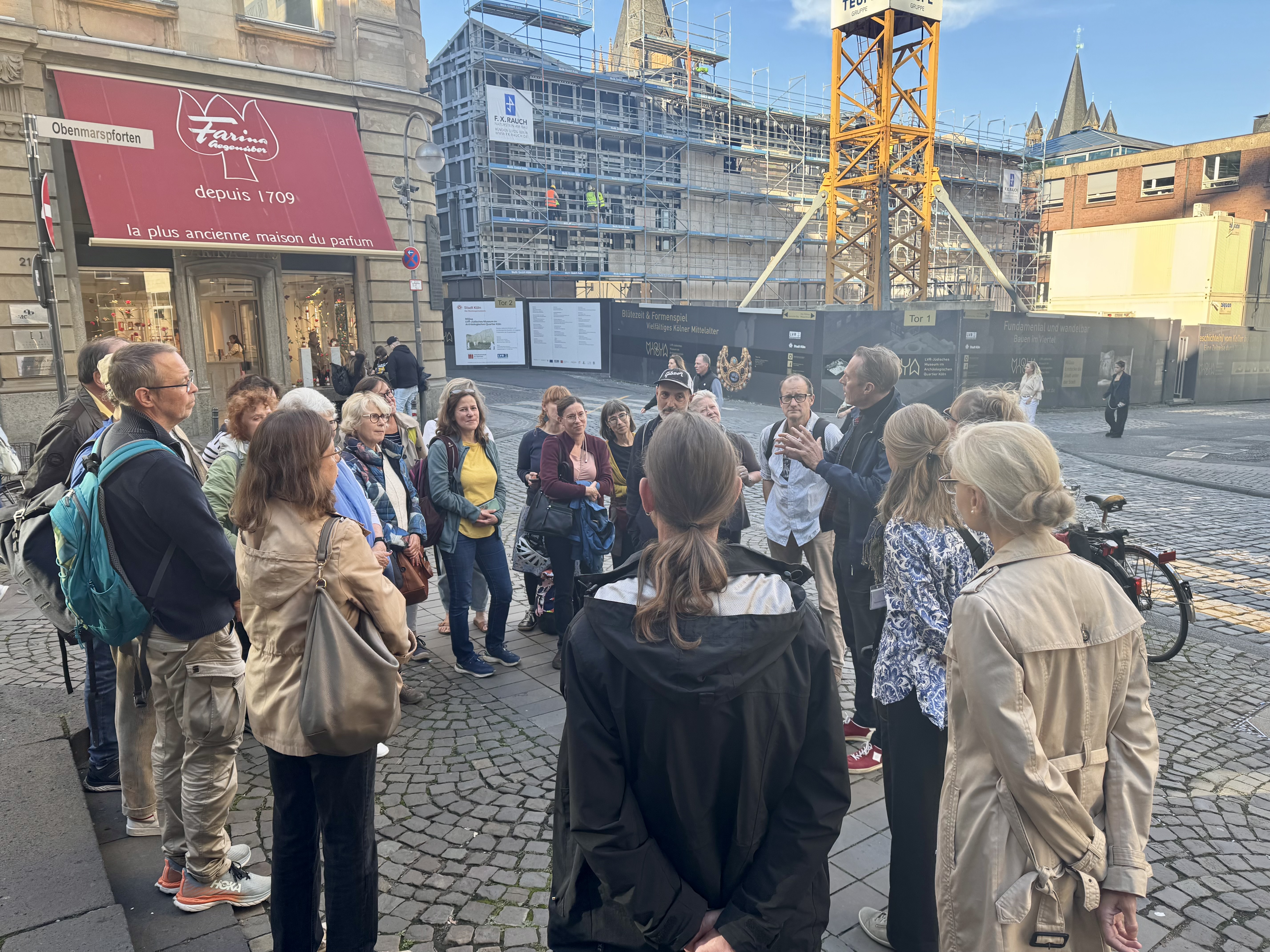 Eine Gruppe Menschen steht in einem Kreis vor einer Baustelle.