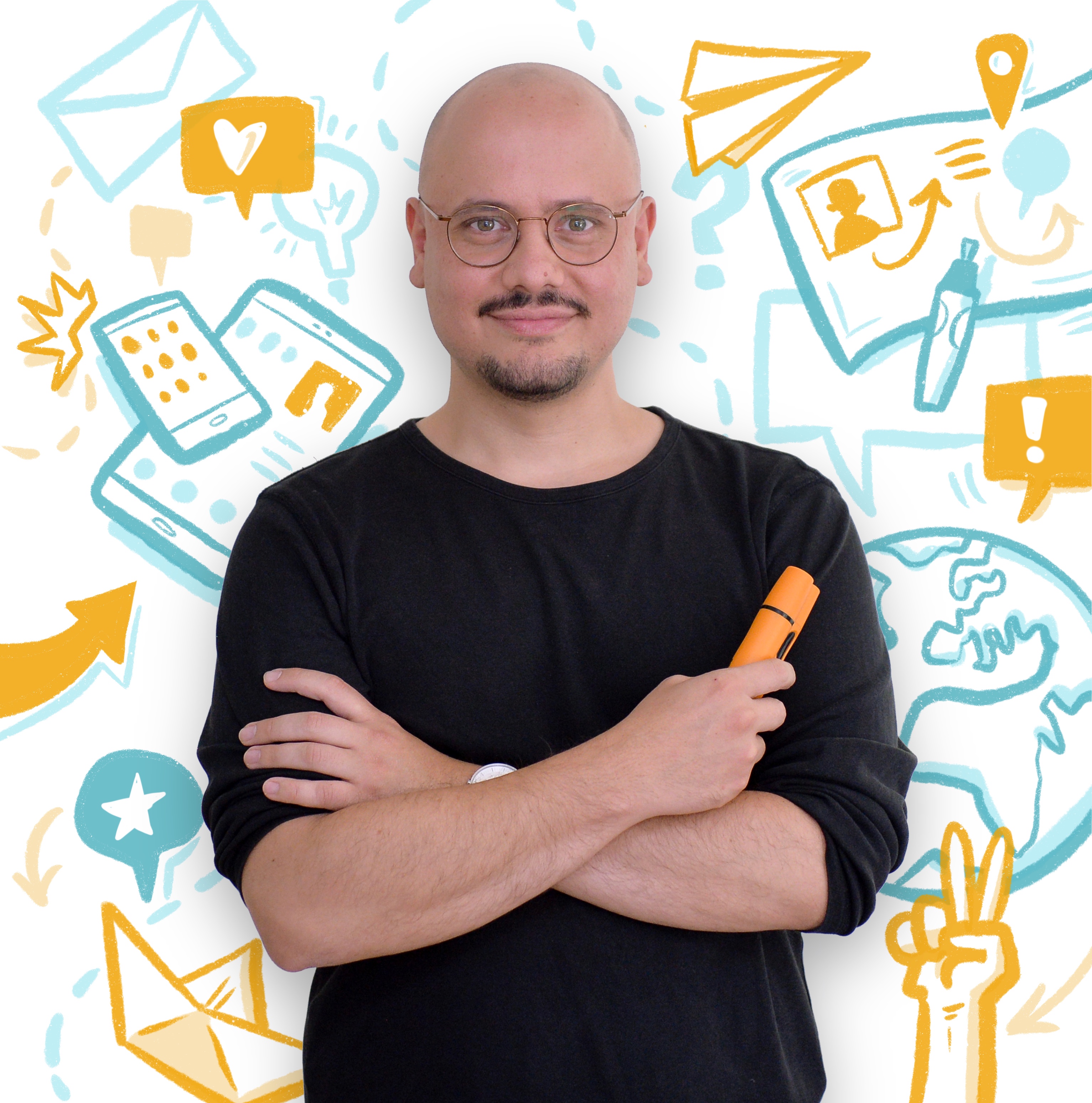 Ein junger Mann mit einer Brille in einem schwarten T-Shirt hält die Arme vor sich gekreuzt. In seiner rechten Hand hält er einen dicken orangenen Stift.