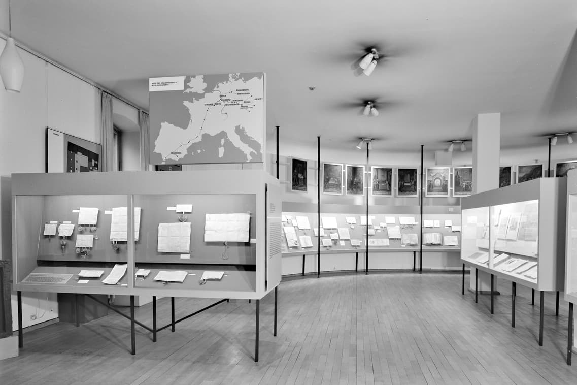 s/w: Blick in einen Ausstellungsraum mit Aufstellern und Glaskästen